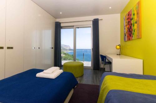 um quarto com 2 camas e uma grande janela em Villa Harmonia by Place OverSea With Indoor Pool em Ponta do Sol