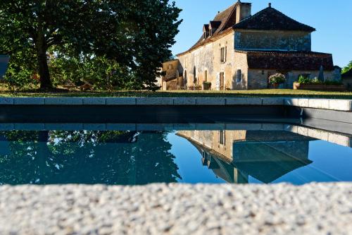 un reflet d'un bâtiment dans une masse d'eau dans l'établissement Les Cieux de Saint-Félix, Maison d'Hôtes & SPA, à Saint-Félix-de-Villadeix