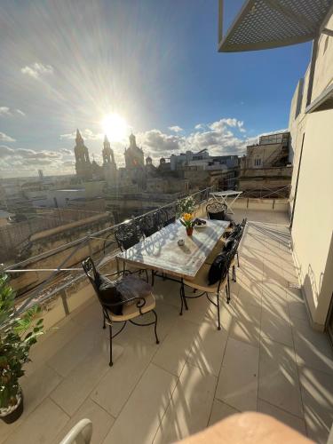 a patio with a table and chairs on a balcony at Sliema Cozy Townhouse with Rooftop View, Prime Spot in Sliema