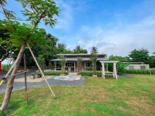 een huis met een tuin met een schommel bij North Pine Forest Homestay บ้านไม้สนโฮมสเตย์ in Ban Mae Pong