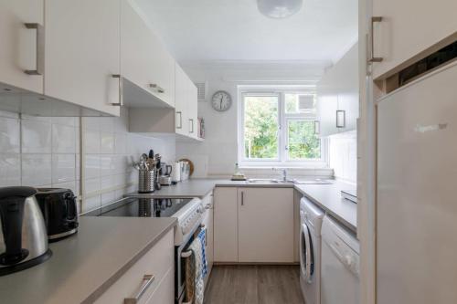 a kitchen with white appliances and a window at Charming One Bed Abode In East Putney in London