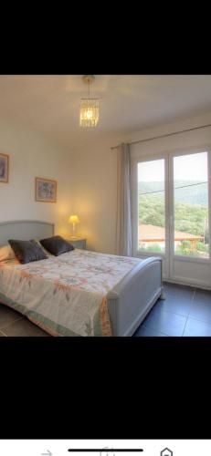 une chambre avec un grand lit et une grande fenêtre dans l'établissement Villa les oliviers, à Olmeto