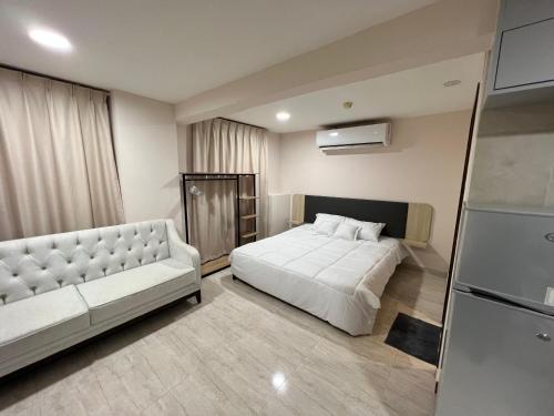 a bedroom with a bed and a couch and a refrigerator at Touch Residence in Al Ḩamīdīyah