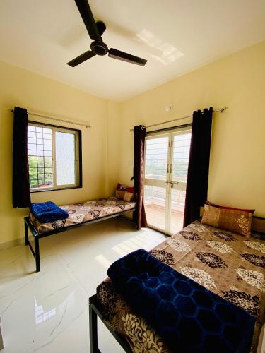 a bedroom with two beds and a ceiling fan at The Peacewood's Homes - Pune's Comfort - Hostel & PG in Pune