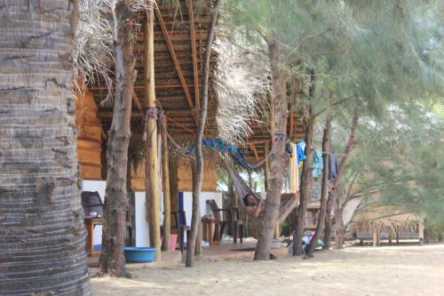a person is sitting under a hut with trees at Sand Dune Beach Resort & Surf Camp in Arugam Bay