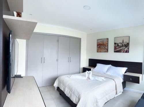 1 dormitorio con 1 cama grande con sábanas blancas en Depa de lujo con piscina y jacuzzi, en Guayaquil
