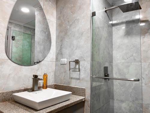 a bathroom with a sink and a shower with a mirror at Depa de lujo con piscina y jacuzzi in Guayaquil