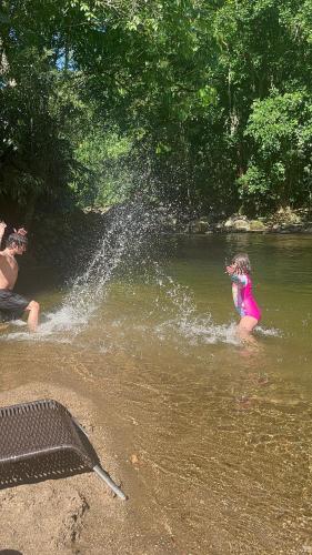 młoda dziewczyna bawiąca się w wodzie w rzece w obiekcie Pousada Rosa dos Ventos Kchu w mieście Cachoeiras de Macacu