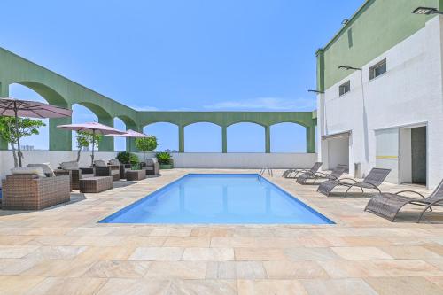 a swimming pool in a patio with chairs and umbrellas at Hotel Nacional Inn Limeira in Limeira