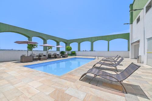 a swimming pool on a patio with chairs and umbrellas at Hotel Nacional Inn Limeira in Limeira