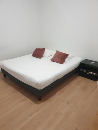 ein weißes Bett mit zwei braunen Kissen darauf in der Unterkunft MAISON A in Saint-Jean-de-Thurigneux