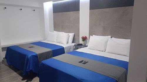 2 camas en una habitación de color azul y blanco en Hotel GALENO, en Veracruz