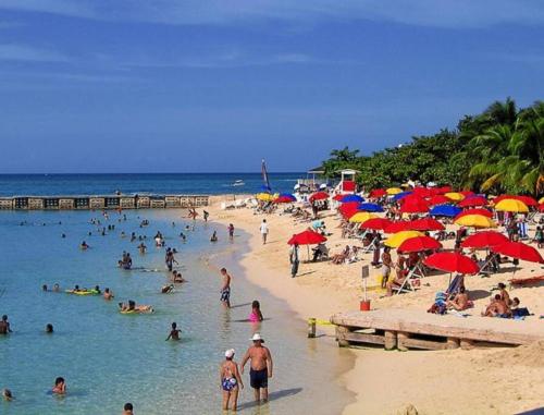 una multitud de personas en una playa con sombrillas en Beach Townhouse, near hip strip, beach, airport, en Montego Bay