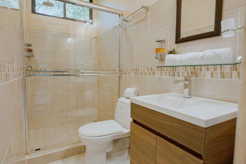 a bathroom with a toilet and a sink and a shower at Mountain Top Park Hotel in Quepos