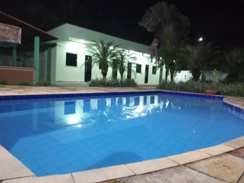 a pool in front of a house at night at Pousada das Acacias in Carananduba
