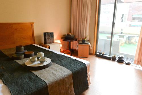 a bedroom with a bed with a table with candles on it at Daedong Hotel in Jeju