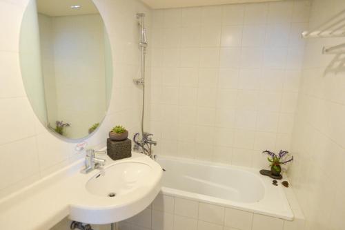 a bathroom with a sink and a tub and a mirror at Daedong Hotel in Jeju