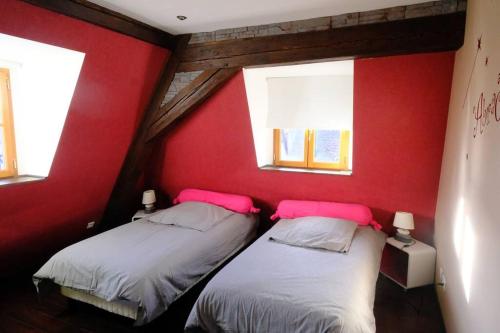 - 2 lits dans une chambre rouge avec 2 fenêtres dans l'établissement Gite centre médiéval Riquewihr, à Riquewihr
