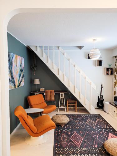 Nordic lodge في روفانييمي: غرفة معيشة بها درج وكراسي برتقالية
