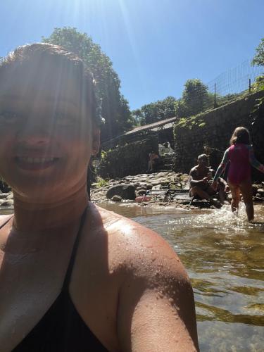 a woman sitting in the water in a river at Pousada Rosa dos Ventos Kchu in Cachoeiras de Macacu