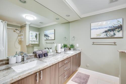 a bathroom with two sinks and a large mirror at Lighthouse Point Home with Pool and Canal Access in Lighthouse Point