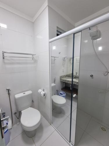 a white bathroom with a toilet and a shower at Spazzio diRoma in Caldas Novas
