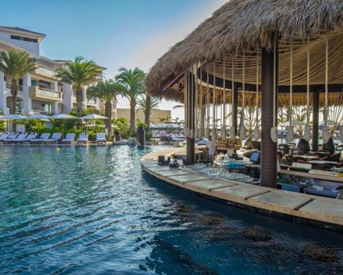 una piscina con sillas y un complejo con palmeras en Cabo Azul, A Hilton Vacation Club en San José del Cabo