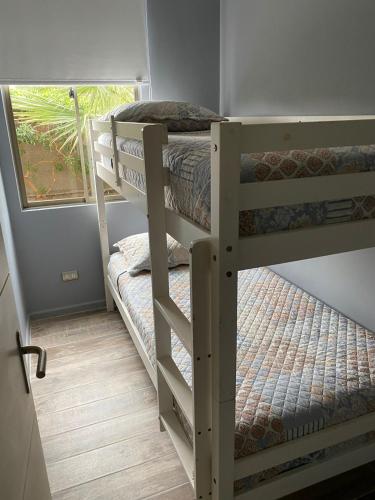 two bunk beds in a room with a window at Condominio Parque Socoroma in Arica