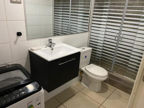 a bathroom with a sink and a toilet and a mirror at Condominio Parque Socoroma in Arica