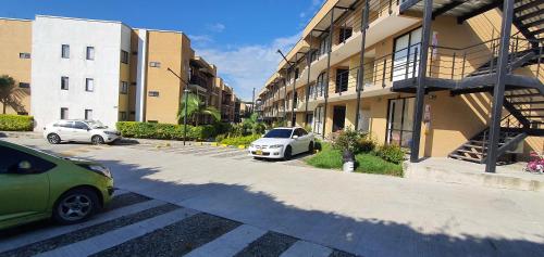two cars parked in a parking lot next to a building at ApartaSol Reserva de la Colina in La Tebaida