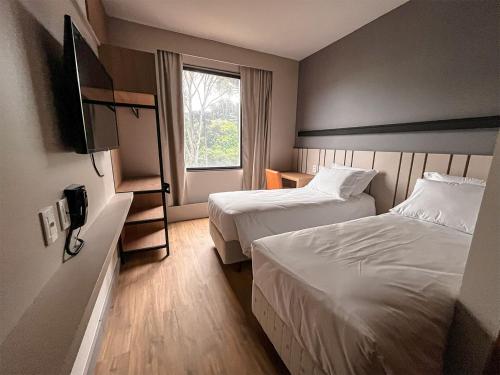 um quarto de hotel com duas camas e uma janela em Plaza Hotel & Boulevard Convention - Vale dos Vinhedos em Garibaldi