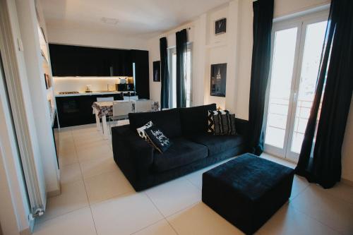 a living room with a black couch and a kitchen at Principato di Baragallo - Free Private Parking in Sanremo