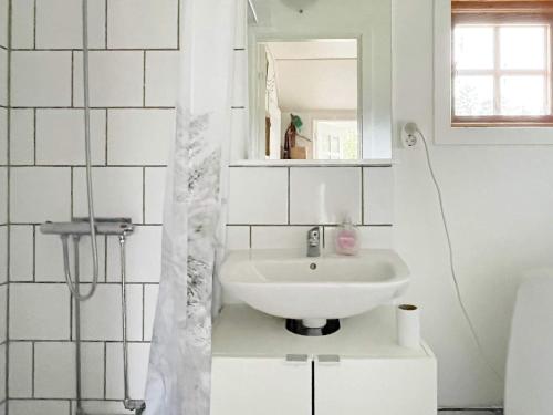 een witte badkamer met een wastafel en een spiegel bij Holiday home VÄDDÖ III in Väddö