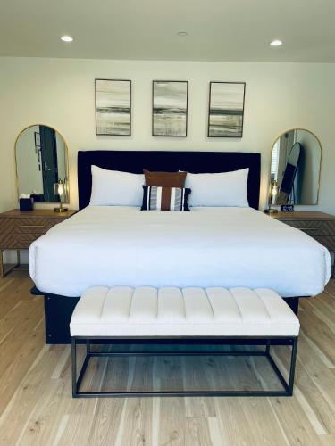 a large white bed with a bench in a room at New Haven Inn in Solvang