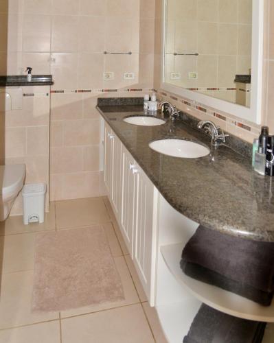 a bathroom with two sinks and a mirror and a toilet at Play Lechi appartement 4 in Kralendijk