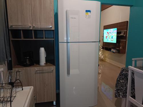 a white refrigerator in a kitchen with a tv at Hollydayhouse in Prudentópolis