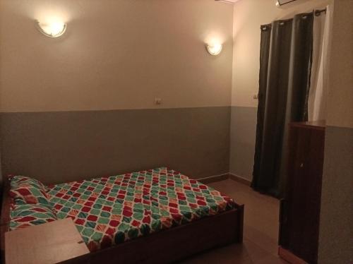 CLAND HOME في واغادوغو: غرفة نوم صغيرة بها سرير ومصباح