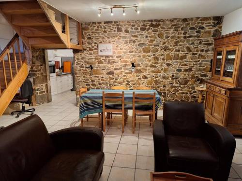 a dining room with a table and a stone wall at Maison en pierre proche mer, commerces et bus in Pordic