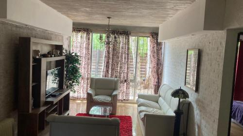 ein Wohnzimmer mit einem Sofa, Stühlen und einem TV in der Unterkunft Casa en San Luis in La Floresta