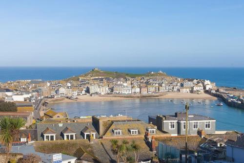 a group of houses on a beach next to the ocean at Sea Salt sea views parking in St Ives