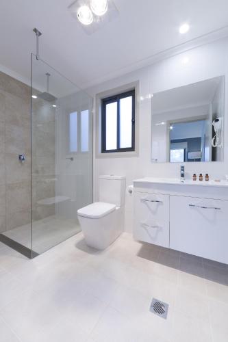 a white bathroom with a toilet and a shower at Alivio Tourist Park Canberra in Canberra