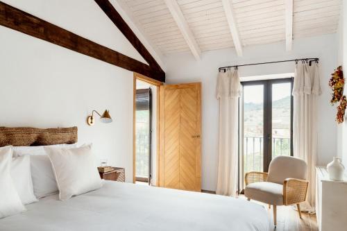 a bedroom with a white bed and a chair at Apartamentos turísticos EL PATIO DEL NOGAL in Guadalupe