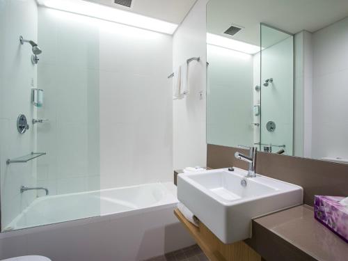 a bathroom with a sink and a shower and a tub at Alpha Hotel Eastern Creek in Blacktown