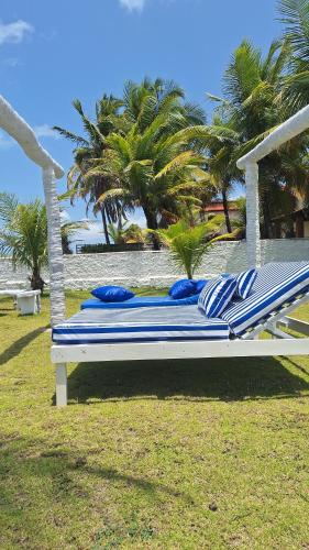a large bed with blue and white pillows on a beach at A 2 passos do paraíso in Rio Tinto