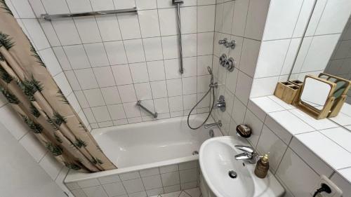 a white bathroom with a tub and a sink at Schöne Wohnung 5 Minuten von München Messe. in Munich