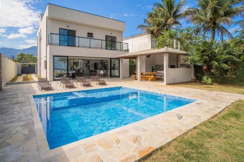 a villa with a swimming pool in front of a house at Paraíso Pé na Areia em Boracéia - Desfrute da conveniência de ter a praia no seu quintal in São Sebastião