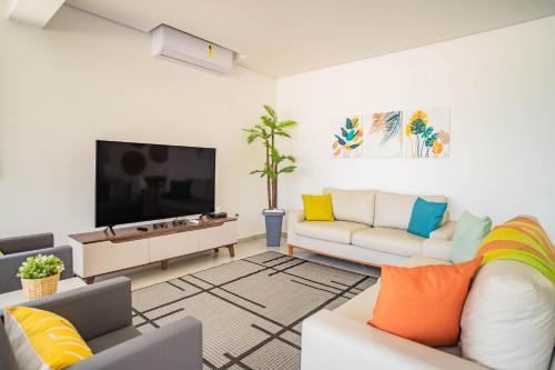 a living room with a couch and a tv at Paraíso Pé na Areia em Boracéia - Desfrute da conveniência de ter a praia no seu quintal in São Sebastião