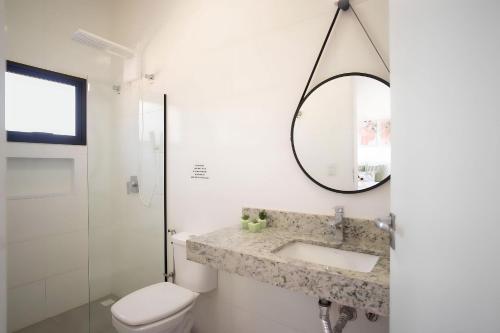 a bathroom with a sink and a toilet and a mirror at Paraíso Pé na Areia em Boracéia - Desfrute da conveniência de ter a praia no seu quintal in São Sebastião