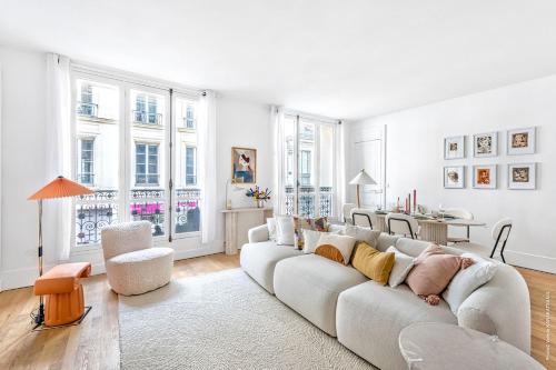 - un salon avec un grand canapé blanc et des fenêtres dans l'établissement Marais - Montmorency 2bdr by B'Your Home, à Paris