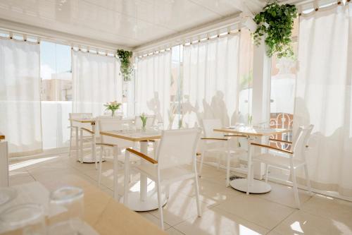 un comedor con sillas blancas, mesas y ventanas en Emblemático F24-Only Adults B&B, en Santa Cruz de Tenerife